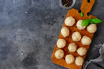 Raw meatballs on a wooden board. Dark background. Copyspace. Cooking chicken meatballs. - obrazy, fototapety, plakaty