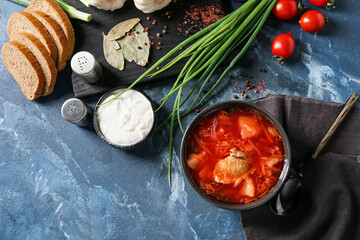 Bowl of tasty borscht and ingredients on color background
