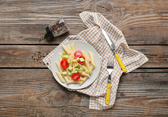 Plate of tasty pasta with vegetables on wooden background