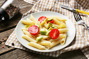Plate of tasty pasta with vegetables on wooden background