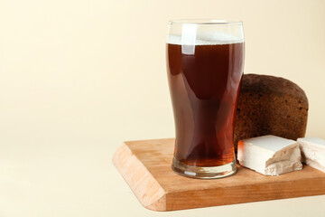Glass of fresh kvass on color background