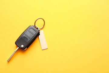 Car key with stylish keychain on color background