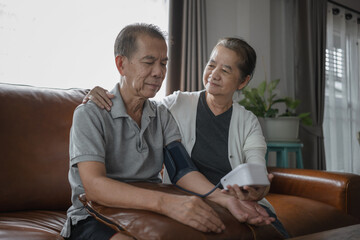 A medium shot of an Asian senior couple checking blood pressure at home, after the blood pressure gauge shows the result they get stressed.