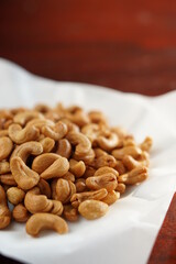 Deep-fried cashew nuts in the fried pad and white dish on wood table.