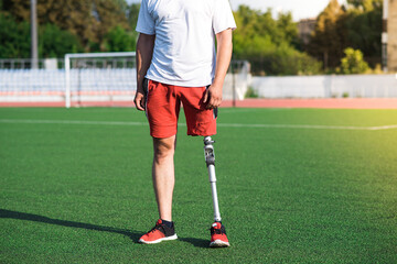 Obraz premium Close up of a man athlete with a prosthesis on his leg standing at the stadium on the field. Sport concept