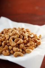 Deep-fried cashew nuts in the fried pad and white dish on wood table.