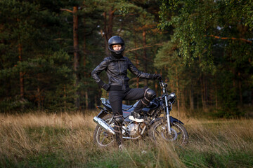 Naklejka premium biker girl in black clothes and black helmet on a motorcycle