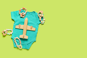 Stylish baby clothes with toys on color background