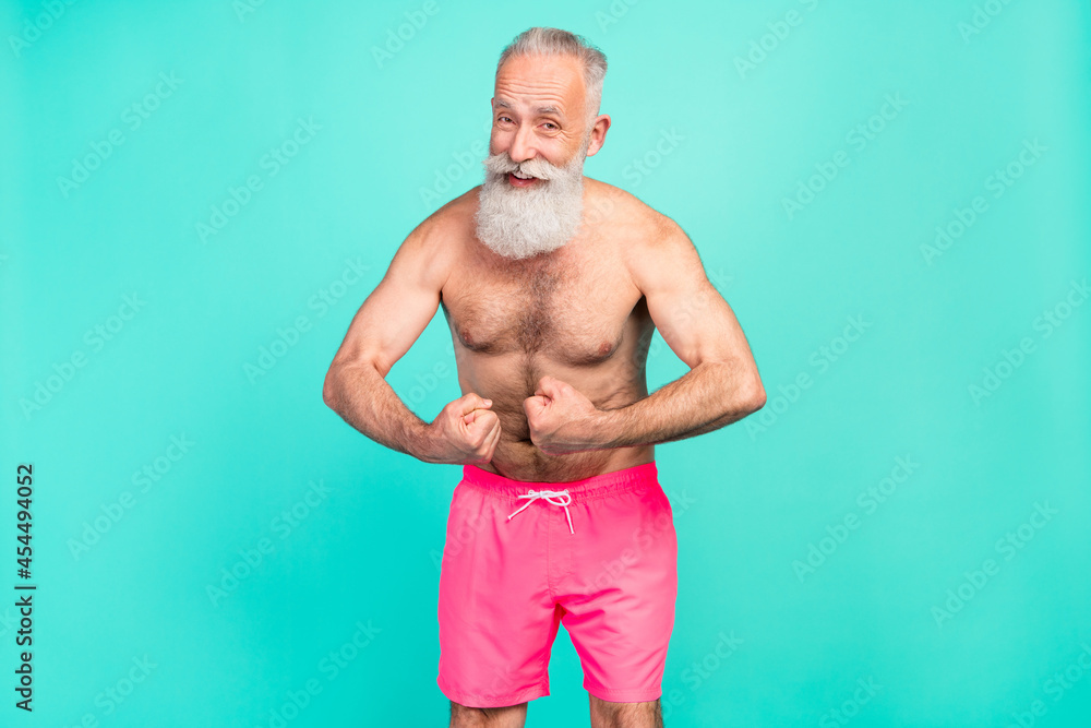 Poster Photo of flirty retired old man show strength arms muscles wear pink shorts isolated teal color background