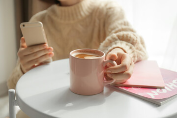 Young woman with cup of coffee at home, closeup