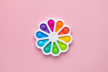 Presses with a finger anti-stress toy pop it on pink background. Colorful silicone poppit toy, bubble fidget, simple-dimple