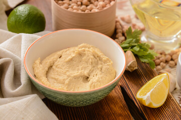 Bowl with tasty hummus and slice of lemon on table