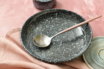 Plate and spoon on color background