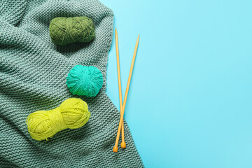 Yarn with knitting needles and plaid on color background