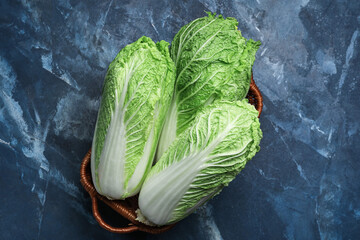 Basket with fresh chinese cabbage on color background