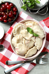 Concept of tasty food with pierogi with cherry on gray textured table