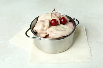 Pot with pierogi with cherry on white textured table