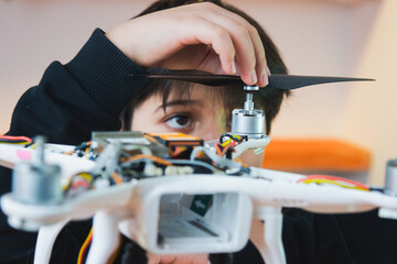 The boy concentrates on putting the propeller on the drone. Extracurricular physics work in the...