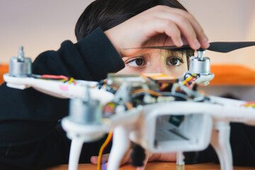 The boy diligently puts the propeller on the drone. Extracurricular physics work in the home lab....