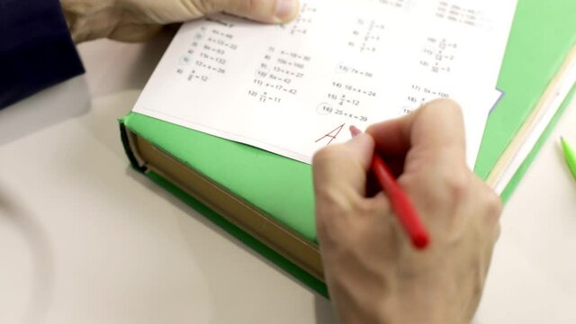 The teacher checks the math test. The man gives a good grade.