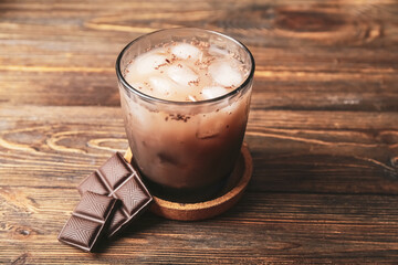 Glass of tasty chocolate milk on wooden background, closeup