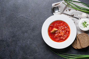 Plate of tasty borscht, sour cream and bread on dark background