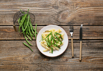 Plate of tasty pasta with vegetables on wooden background