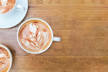 Latte coffee cup with flower Latte art on wooden table in top view shot