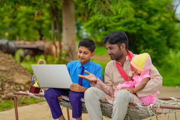 Education concept :cute indian school boy using laptop and giving some information to his father.