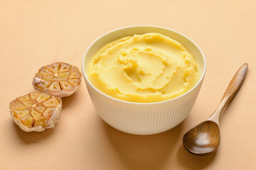 Bowl of tasty mashed potatoes with garlic on color background