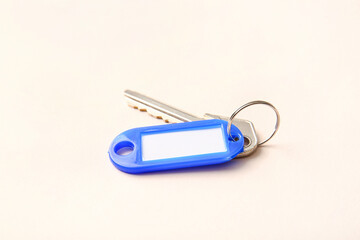 Plastic tag with key on light background, closeup