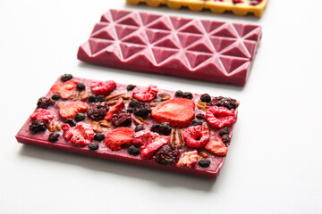 Handmade chocolate bars with fruits, berries and nuts on white background, closeup
