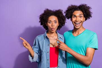 Photo of shocked couple crazy people dark skin couple point finger empty space isolated on purple color background