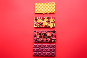 Obraz premium Handmade chocolate bars with fruits, berries and nuts on color background
