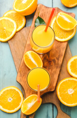 Glasses of tasty orange juice on color wooden background