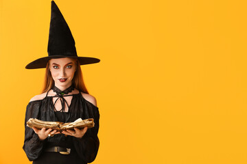 Young witch with spell book on color background