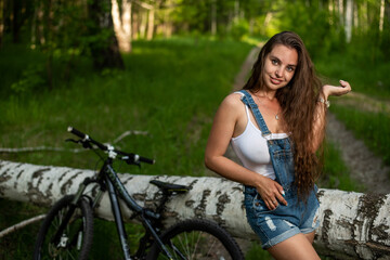 Fototapeta na wymiar Young woman is resting while cycling in the forest