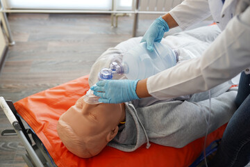 Nursing students are practicing how to provide oxygen administration to the patient by a doll of patient in the simulation of virtual presence in the hospital.