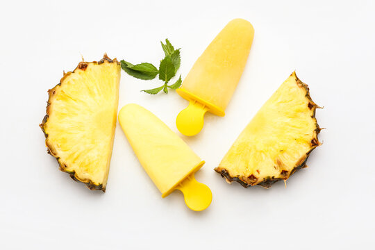Tasty pineapple popsicles on white background