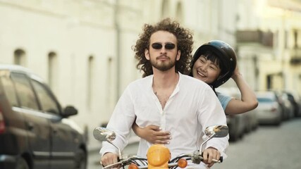 Smiling couple riding scooter on the street at summer