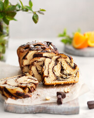 Chocolate Babka with oranges. Orange pastries on a marble table. Homemade cake. Brooklyn cuisine. Chocolate pieces and hazelnuts