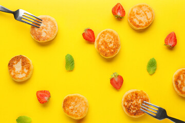 Cottage cheese pancakes, strawberry and forks on color background