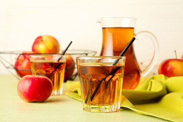 Jug and glasses of tasty apple juice on color wooden table