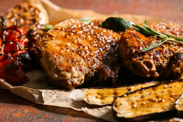 Tasty pork steaks and grilled vegetables on grunge background, closeup