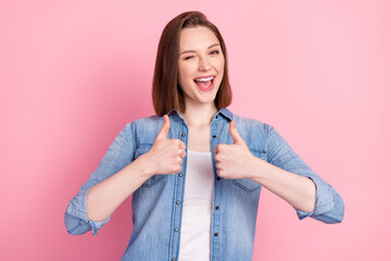 Photo portrait of girl smiling showing thumb-up like gesture winking blinking isolated pastel pink...