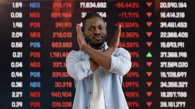 Young man showing stop gesture on stock market background, money loss, crisis