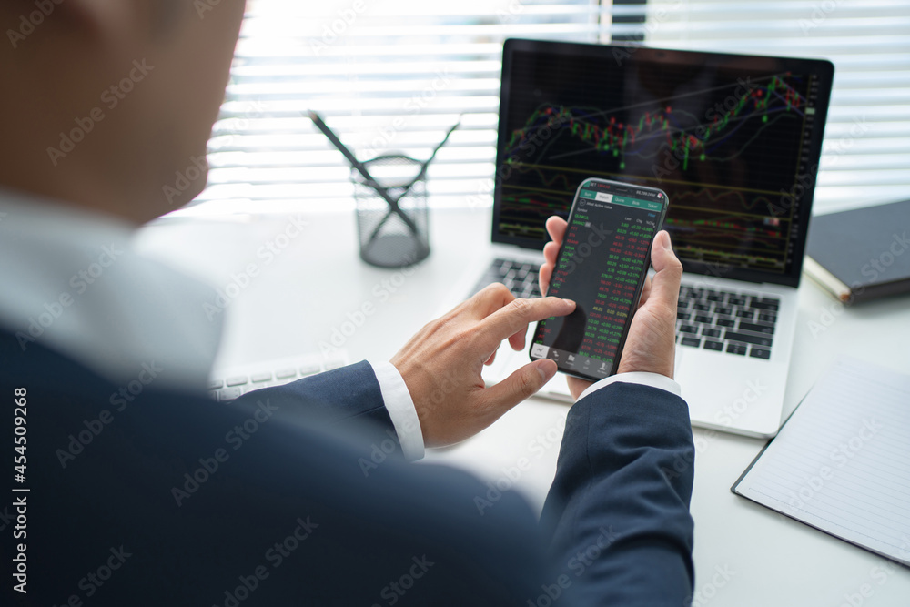 Poster businessman using smartphone. he is analyzing data with trading charts.