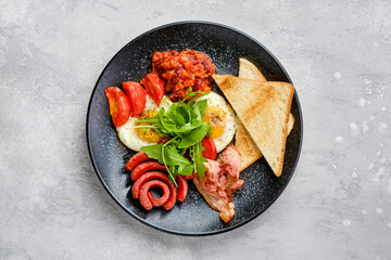 Top view of fried eggs with sausage, bacon, tomatoes and beans