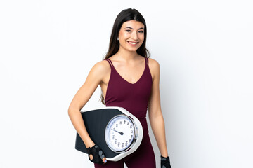 Young sport woman over isolated white background with weighing machine