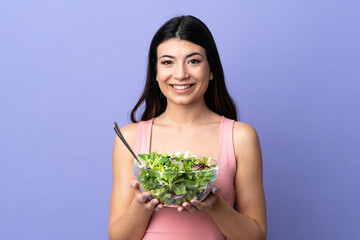 Young woman with salad over isolated purple background